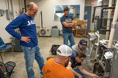 Professor Jason Stutes and students look at HVAC unit.