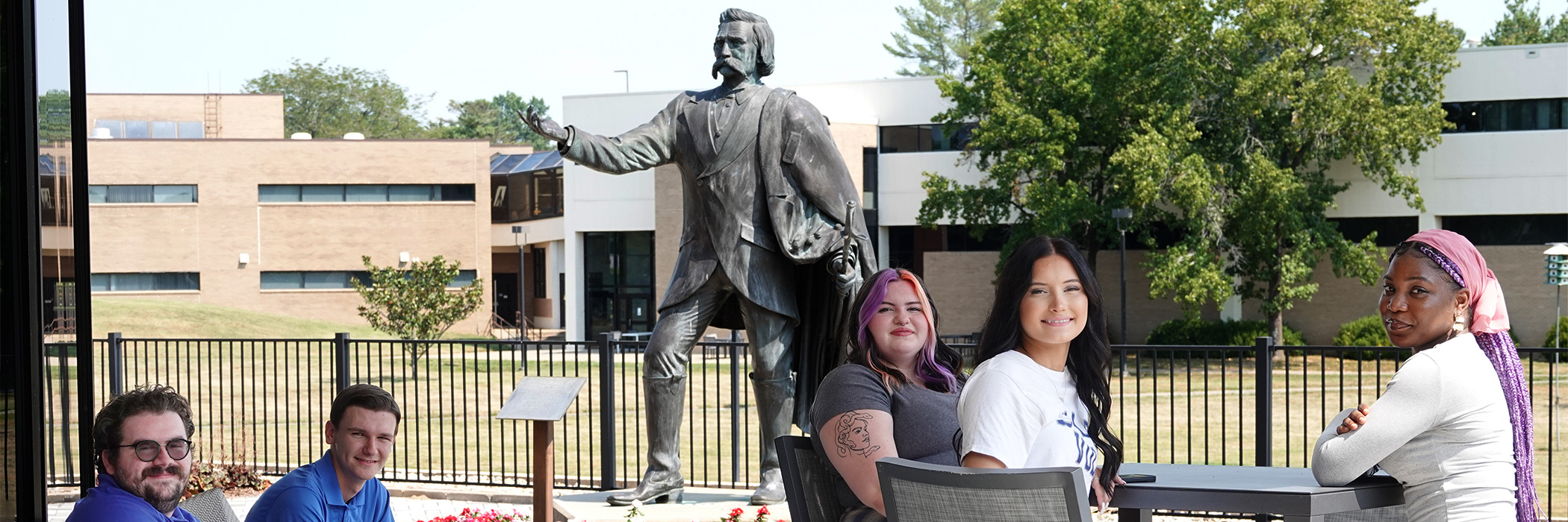 Students sitting outdoors next to John A. Logan statue.