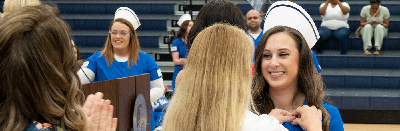 Student receives pin at ADN nurse pinning ceremony.