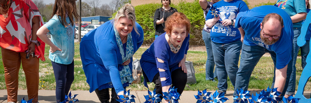 Jo Poshard and others place blue pinwheels on JALC's campus as part of the Poshard Foundation for Abused Children's efforts to bring awareness to their cause.