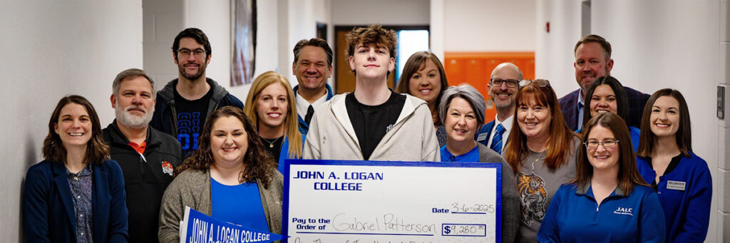 Gabriel Patterson with scholarship check surrounded by group of people.